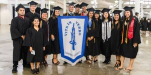 Students holding the Vito in Verbo banner posing for the camera at commencement