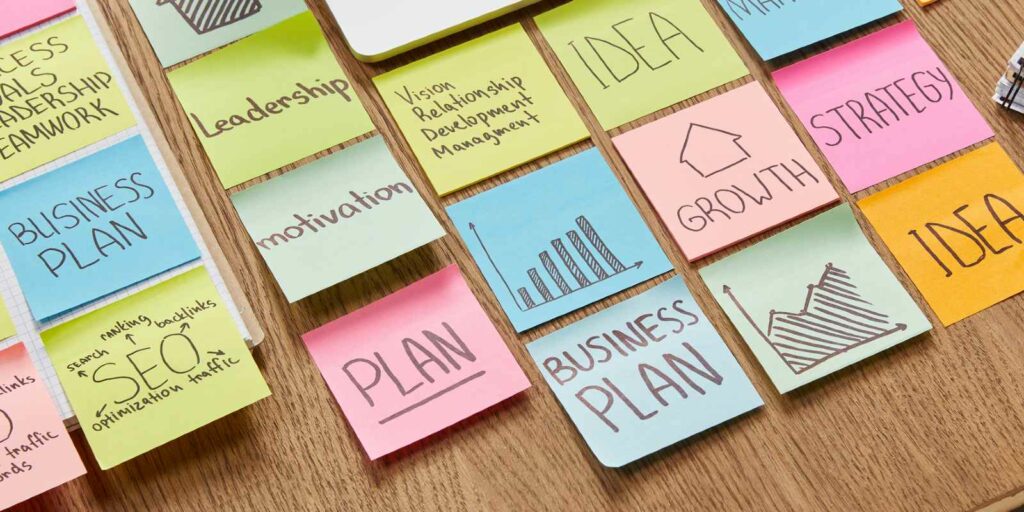 high angle view of paper stickers with business strategy and laptop on tabletop